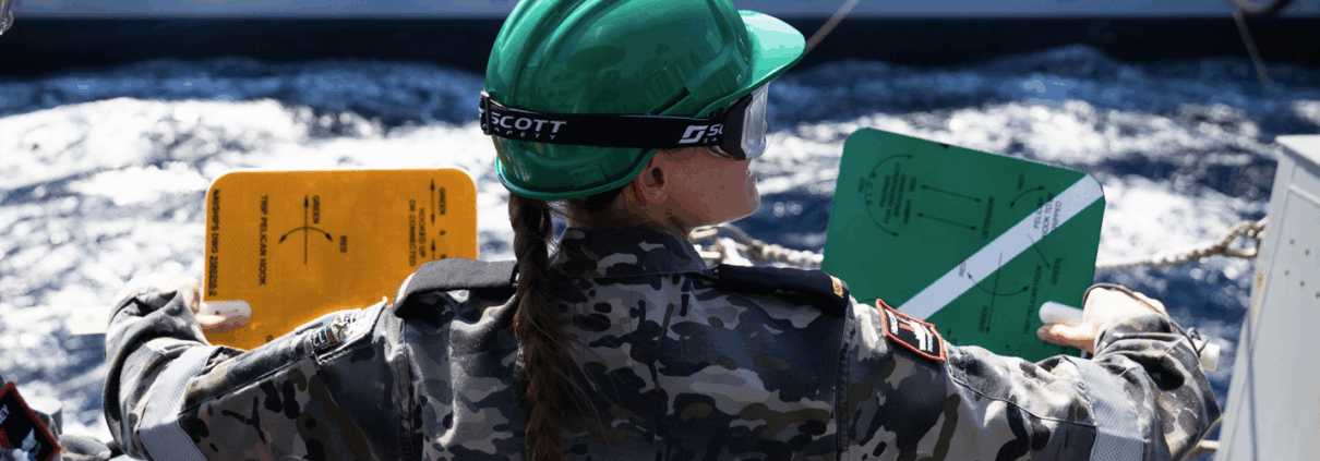 Seaman Boatswains Mate Stacey Conway signals to USNS John Lewis during a Replenishment at Sea with the fleet replenishment oiler ship.