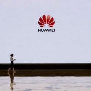 A member of Huawei's reception staff walks in front of a large screen displaying the logo in the foyer of a building used for high profile customer visits and displays at the company's Bantian campus on April 12, 2019 in Shenzhen, China.