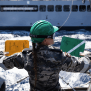 Seaman Boatswains Mate Stacey Conway signals to USNS John Lewis during a Replenishment at Sea with the fleet replenishment oiler ship.