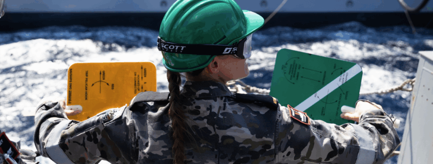 Seaman Boatswains Mate Stacey Conway signals to USNS John Lewis during a Replenishment at Sea with the fleet replenishment oiler ship.